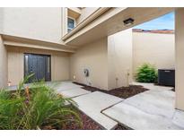 Beautiful front entryway featuring a charming door, beige siding, and lush tropical landscaping at 106 Madrid Dr, Casselberry, FL 32707