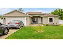 Charming single-story home with attached garage, well-maintained lawn, and inviting front porch at 353 Cimarron Ct, Kissimmee, FL 34759