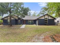 Charming home featuring a striking black exterior, a well-manicured lawn, and mature trees at 5340 Jones Rd, St Cloud, FL 34771