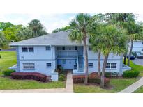 Charming two-story condo with tropical landscaping and exterior stairs leading to the second floor entrance at 576 Fairways Ln # M103, Ocala, FL 34472