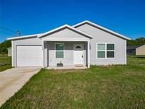 Charming single-story home featuring a well-manicured lawn, attached garage, and a classic white front door at 12388 Se 106Th Ave, Belleview, FL 34420