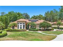 Charming home featuring a beautiful lawn, lush landscaping, and solar panels on the roof at 128 Lake Region Cir, Winter Haven, FL 33881