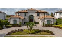Elegant two-story home with a tile roof, manicured landscaping, and a circular driveway at 13125 Casabella Dr, Windermere, FL 34786