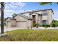 Beautiful two-story home featuring a well-manicured lawn, three-car garage, and eye-catching stonework at 13640 Dornoch Dr, Orlando, FL 32828