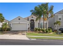 Charming single-story home featuring a well-manicured lawn and a two-car garage with palm trees at 2380 Kaley Ridge Rd, Clermont, FL 34715