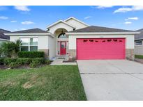 Charming single-Gathering home showcasing a well-manicured lawn and inviting red garage door at 2535 Oneida Loop, Kissimmee, FL 34747