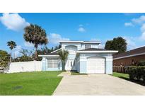 Charming light blue two-story home featuring an attached garage, landscaped yard, and well-manicured lawn at 2601 Spring Hill Dr, Kissimmee, FL 34743