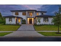 Stunning two-story home featuring a modern design with a paver driveway, manicured lawn and sophisticated front entrance at 5762 Emerington Cres, Orlando, FL 32819