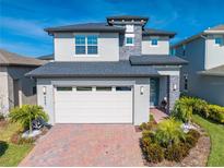 Charming two-story home with brick driveway, attached two-car garage, manicured landscaping, and welcoming front entry at 6667 Alder Rd, Harmony, FL 34773