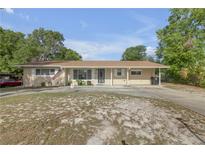 Charming single-story home with a covered parking area and well-maintained front lawn at 825 Second St, Orange City, FL 32763