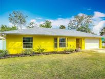 Charming yellow single-story home featuring a well-maintained lawn and a two-car garage at 110 Riverside Ter, Edgewater, FL 32141