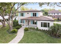 Charming two-story home featuring lush landscaping, light blue shutters, and a welcoming tile roof at 702 S Lake Adair Blvd, Orlando, FL 32804