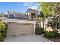 Charming two-story home with a beige exterior, attached two-car garage, and manicured landscaping at 9244 Pecky Cypress Way, Orlando, FL 32836