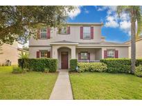Charming two-story home features a well-manicured lawn, red shutters, and a welcoming front porch at 987 Alston Bay Blvd, Apopka, FL 32703