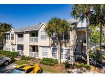 Tan two-story condo building with balconies and exterior stairwell, set amongst palm trees on a sunny day at 1089 S Hiawassee Rd # 314, Orlando, FL 32835