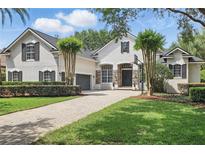 Stately two-story stucco home with a paver driveway, lush landscaping, and a basketball hoop above the garage at 11345 Preserve View Dr, Windermere, FL 34786