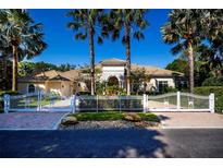 Stunning estate with white fence and brick driveway, showcased with palm trees against a clear, sunny sky at 4 Island Dr, Lake Mary, FL 32746