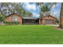 Well-maintained brick house featuring manicured landscaping, flowers, and a manicured lawn at 445 Songbird Way, Apopka, FL 32712