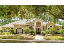 Stately home featuring a tiled roof, arched windows, mature landscaping, and a welcoming entrance at 612 Stonefield Loop, Lake Mary, FL 32746