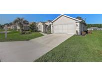 Single-story home with an attached garage, long driveway, and beautiful landscaping at 1900 Nw 57Th Ct, Ocala, FL 34482
