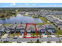 Stunning aerial view of a home in a lakeside community with lush landscaping and a paver driveway at 5648 Cedar Chase Dr, St Cloud, FL 34771