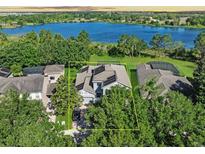 Aerial view of a two-story home featuring solar panels and a well-manicured lawn near a serene lake at 6152 Meriwether, Winter Garden, FL 34787
