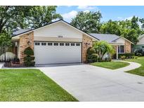 Two car garage with a lush green lawn and landscaped shrubs at 1013 Glensprings Ave, Winter Garden, FL 34787