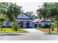 Elegant white home featuring a circular driveway, black trim, manicured lawn, and lush landscaping at 6550 Cartmel Ln, Windermere, FL 34786