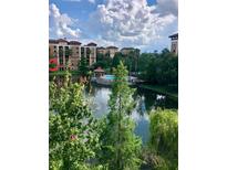 Scenic lake view of the community pool, gazebo, and multi-story buildings on a bright and sunny day at 12539 Floridays Resort Dr Dr # 208D, Orlando, FL 32821