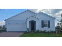 Charming single-story home featuring a two-car garage, well-manicured lawn, and elegant architectural details at 14599 Crestavista Dr, Clermont, FL 34714