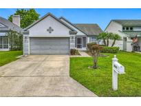 Charming home features a well-manicured lawn, mature landscaping, and a two-car garage at 2885 Autumn Green Dr, Orlando, FL 32822