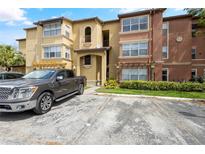 Inviting multi-story condo building featuring manicured landscaping, pergola and ample parking spaces on a sunny day at 5156 Conroy Rd # 1124, Orlando, FL 32811