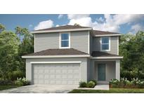 Charming two-story home featuring gray siding, a two-car garage, and lush landscaping at 7335 Capstone Dr, Groveland, FL 34736