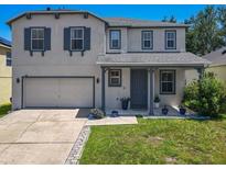Charming two-story home featuring a well-manicured lawn, gray shutters, and a two-car garage at 1225 Greenley Ave, Groveland, FL 34736