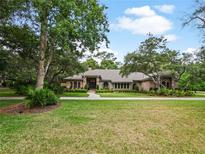 Charming single-story home with a lush lawn, mature trees, and brick facade, providing great curb appeal at 554 Estates Pl, Longwood, FL 32779