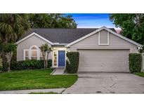 Charming single-story home with a well-manicured lawn, inviting blue door, and attached two car garage at 1027 Dees Dr, Oviedo, FL 32765