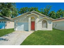 Charming single-story home with a well-manicured lawn, red door, and attached garage at 1073 Hamlet Dr, Maitland, FL 32751