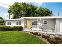 Charming one-story home with a well-manicured lawn, minimalist yard art, and a bright yellow front door at 2707 Chelsea St, Orlando, FL 32803