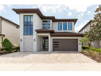 Contemporary two-story home with a brick driveway and modern architectural details at 7928 Jacks Club Dr, Kissimmee, FL 34747