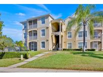 Condo building featuring tan siding, screened balconies, and well-maintained landscaping at 8107 Coconut Palm Way # 102, Kissimmee, FL 34747