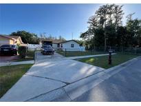 Charming single-story home featuring a well-maintained lawn, gated driveway and mature trees at 8445 Quisqualis Dr, Orlando, FL 32822