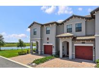 Charming townhome exterior with brick driveway, lake view, and red garage door at 8549 Zoeller Hills Dr, Davenport, FL 33896