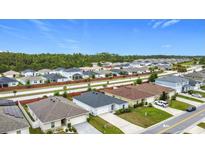 Wide aerial view of a suburban neighborhood with well-maintained homes and green spaces on a bright day at 16369 Yelloweyed Dr, Clermont, FL 34714