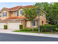 Two-story townhome showing the front entrance, a two car garage, and well manicured shrubbery at 1998 Michael Tiago Cir, Maitland, FL 32751
