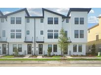 Modern townhome exterior featuring white siding, black trim, and well-maintained landscaping at 15489 Hamlin Park Drive, Winter Garden, FL 34787