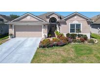 Charming single-story home featuring a two-car garage, brick walkway, and vibrant flower beds at 2977 White Cedar Cir, Kissimmee, FL 34741