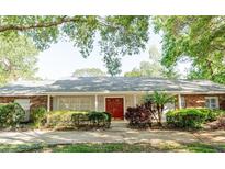 Charming single-story home featuring a red double door, light gray siding, brick accents, and lush landscaping at 604 Blue Lake Dr, Longwood, FL 32779