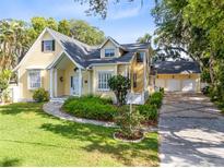 Charming yellow two-story home with a well-manicured lawn and a three car garage at 910 Cypress Ave, St Cloud, FL 34769