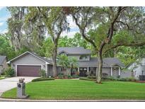 Charming two-story home features a lush green lawn, mature trees, and a welcoming front entrance with double doors at 934 Deerwood Loop, Longwood, FL 32779