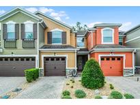 Colorful townhouses with garage, manicured shrubs and bushes, and paved driveway on a bright sunny day at 9349 Sweet Maple Ave, Orlando, FL 32832